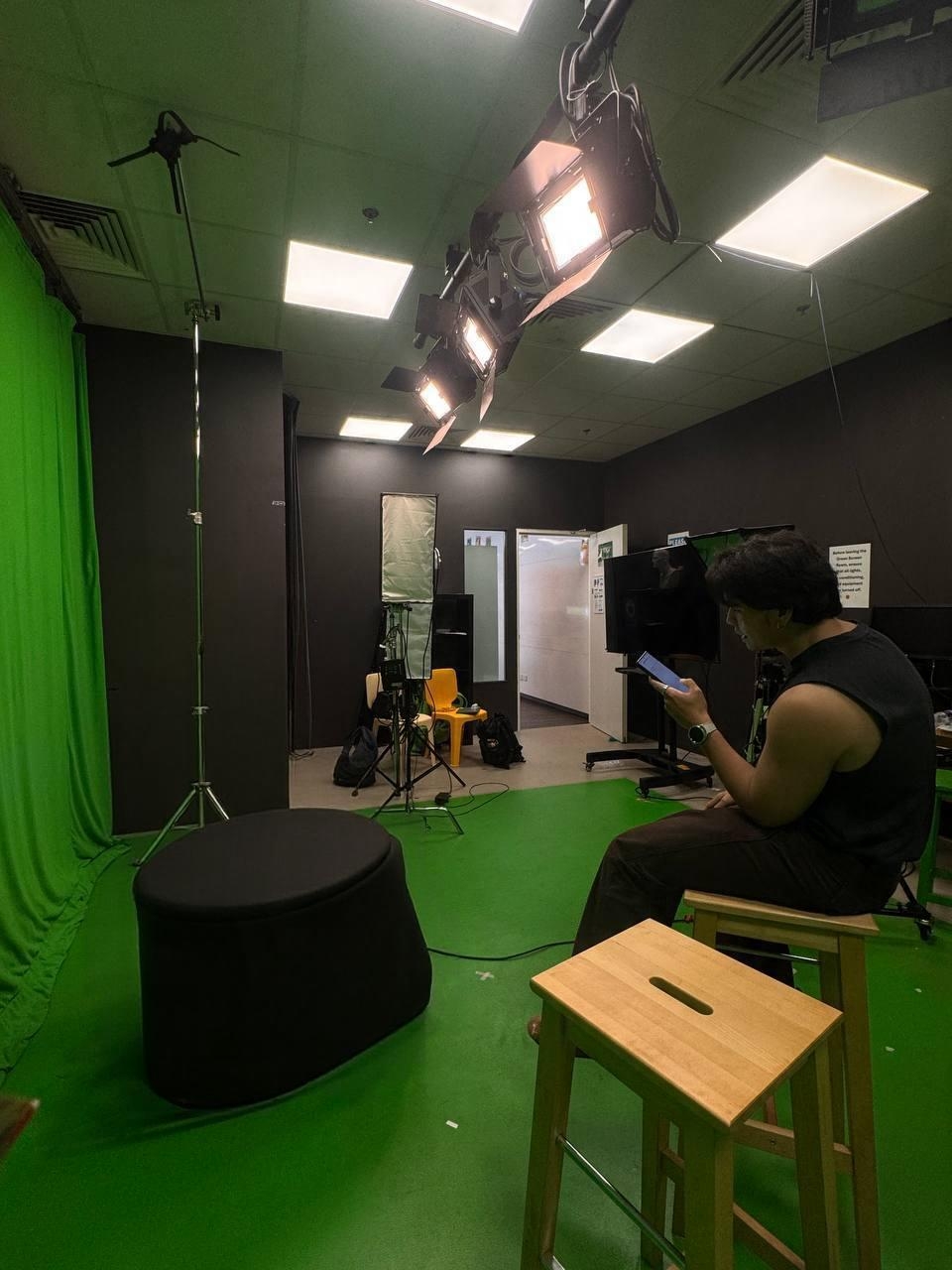 NextTake Labs founder seated beside lights and a green screen in a production studio